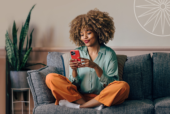 young woman sitting on a comfy couch and using her phone